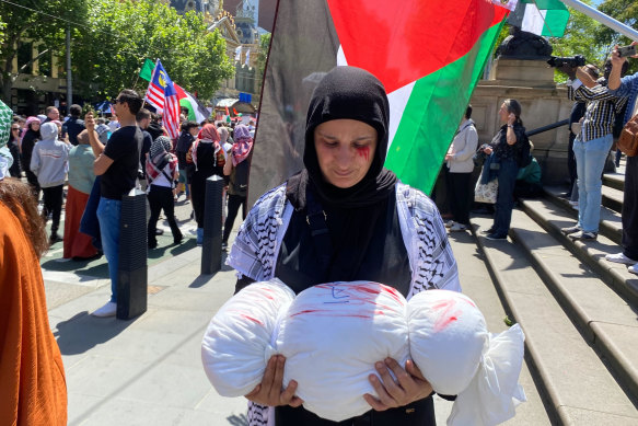 Ferdos Elsabaa carries a white bundle to signify a dead child during a free Palestine rally on Sunday.