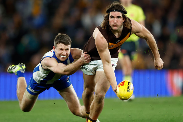 Hawthorn’s Jai Newcombe lays off a handball under pressure from airborne Kangaroo Liam Shiels.