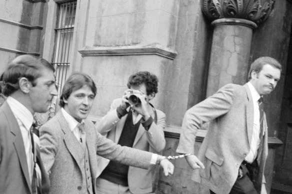 Christopher Dale Flannery (second from left) is led handcuffed into Melbourne’s City Watch House in October 1981 to be charged with the murder of Roger Wilson.