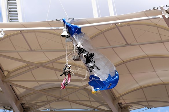 The parachutist hangs from the stadium roof.