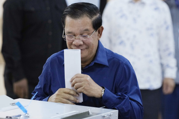 Cambodian Prime Minister Hun Sen of the Cambodian People’s Party (CPP) kisses a ballot before voting.