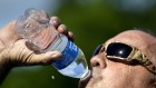 Robert Harris drinks water while taking a break from digging fence post holes in Houston, Texas.