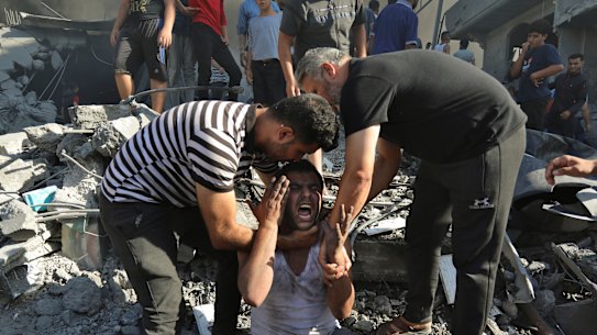 Palestinians comfort a crying man after losing relatives under the rubble of a destroyed house following an Israeli airstrike in Gaza City,
