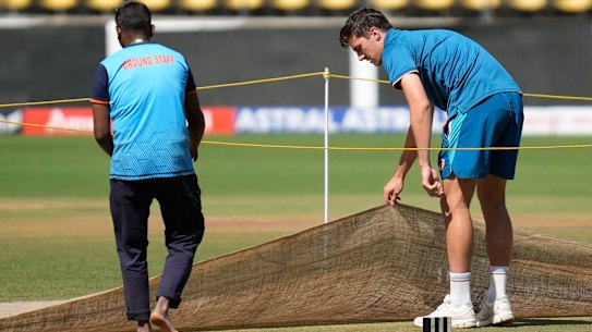 Australian captain Pat Cummins removes the cover to inspect the pitch ahead of the first cricket in Nagpur, India.