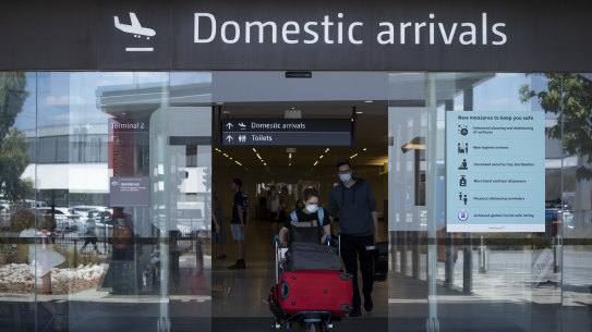 PERTH, AUSTRALIA - JANUARY 08:  Passengers wearing PPE arrive from Brisbane at Perth Airport on January 8, 2021 in Perth, Australia. The international arrival cap has been lowered and all domestic and international air travellers are now required to wear masks as Australia takes precautions due to concerns over a new Covid-19 strain. Brisbane will enter a three-day lockdown tonight after a cleaner working at a quarantine hotel tested positive for the new Covid-19 variant. (Photo by Matt Jelonek/Getty Images)