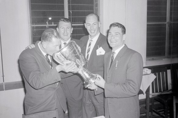 Melbourne coach Norm Smith drinks a victory toasts from the premiership cup, watched by John Beckwith, John Lord and Barassi in 1960. 