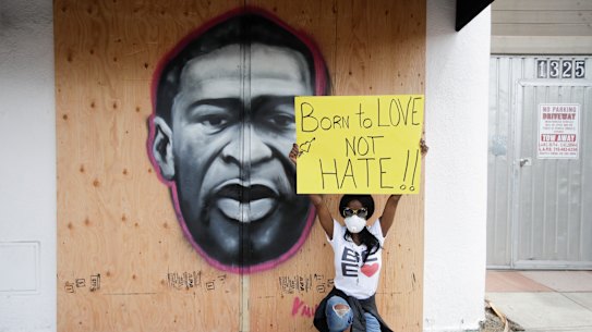 In Los Angeles, Mecca Dyas holds a sign next to an image of George Floyd.