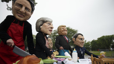 Activists wear masks in the likeness of, from left, Justin Trudeau, Theresa May, Shinzo Abe, Donald Trump and Emmanuel Macron at a G7 protest in Quebec.