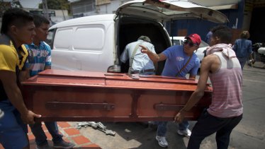 Relatives carry the coffin containing the remains of Daniel Marquez, a victim of the catastrophic blaze that swept through a police station jail a in Valencia, Venezuela.