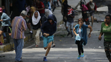 Anti-government protesters run during clashes with security forces as they show support for an apparent mutiny by a Venezuelan National Guard unit.