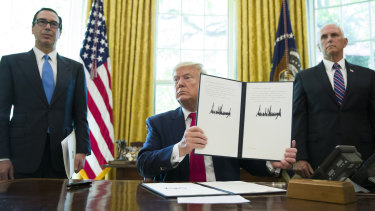 President Donald Trump holds up a signed executive order to increase sanctions on Iran.