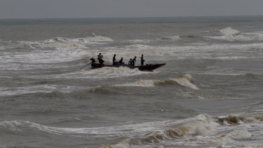 Indian fishermen attempt to bring their boat ashore amid strong winds at Chandrabhaga beach in the Puri district of eastern Odisha state, India.
