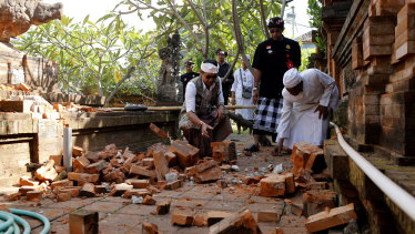 Balinese man collect stones from a damaged temple in Bali, Indonesia on Tuesday.