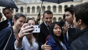 France's President Emmanuel Macron, centre, poses with students after a military ceremony at the Hotel des Invalides, in Paris.