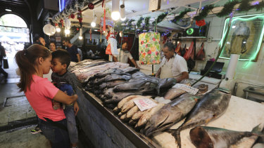 A shopper holds her son as she buys fish at the Central Market, the main market of Santiago, Chile, on Thursday.