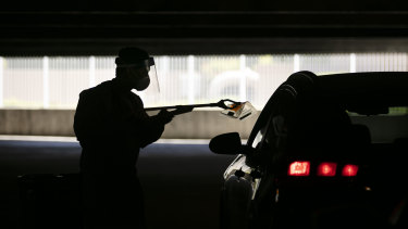 A healthcare worker uses a grabber to collect a nasal swab sample at a COVID-19 drive-through testing site in California.