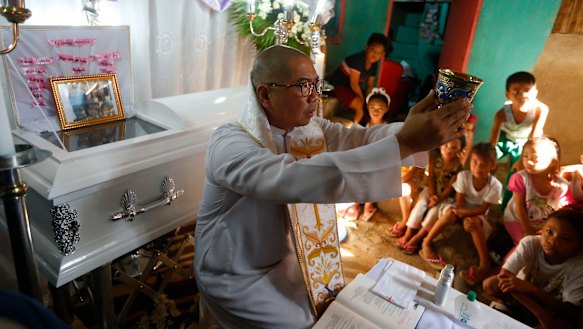 The mother of the slain girl Myka Ulpina sprinkles holy water at her coffin during a mass.