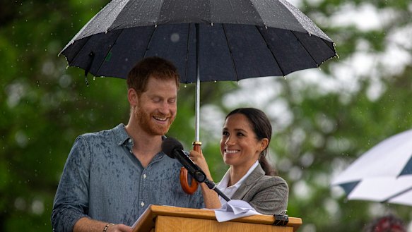 Dream team: Meghan shelters Prince Harry while he speaks at a community picnic.