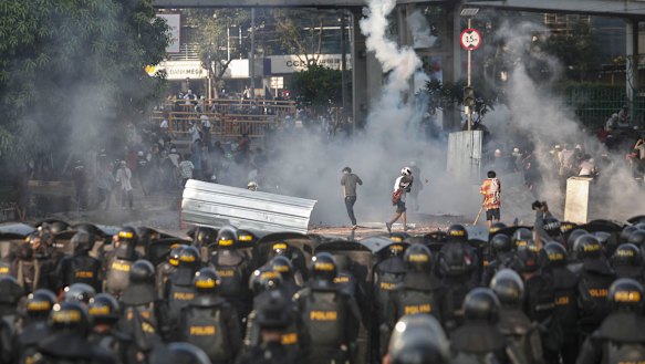 Indonesian riot police officers fire a tear gas launcher to disperse supporters of Indonesian presidential candidate Prabowo Subianto.