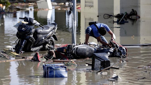 A man tries to get his motorbike upright at a tsunami-devastated area in Talise beach, Palu.