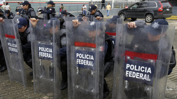 Mexican federal police in riot gear receive instructions at the border crossing between Guatemala and Mexico, in Ciudad Hidalgo, Mexico, on Friday.