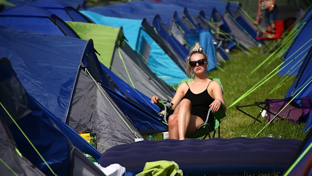 A festivalgoer sits in the sunshine amongst tents at the Glastonbury Festival in England on Friday.