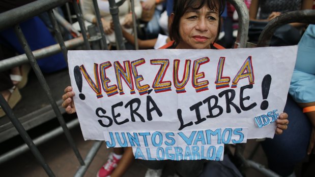 A supporter of opposition leader and self-proclaimed interim president of Venezuela Juan Guaido, holds a sign that reads in Spanish "Venezuela will be free! We will do it together." 