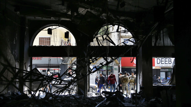 Lebanese army soldiers and people gather near a branch of the Libano Francaise Bank that was set on fire by anti-government protesters during confrontations that began on Monday night in the northern city of Tripoli, Lebanon.