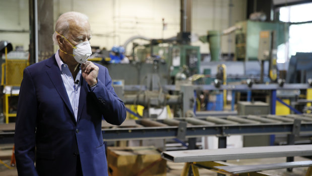 Democratic presidential candidate Joe Biden adjusts his mask during a tour of McGregor Industries, a metal fabricating facility