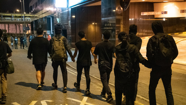 Anti-government protesters hold hands while leaving Hong Kong Polytechnic University to surrender to the police on November 22.