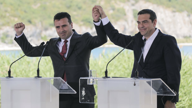 Greek Prime Minister Alexis Tsipras, right and his Macedonian counterpart Zoran Zaev, raise their hands during a signing agreement for Macedonia's new name in the village of Psarades, Prespes Greece, on Sunday.