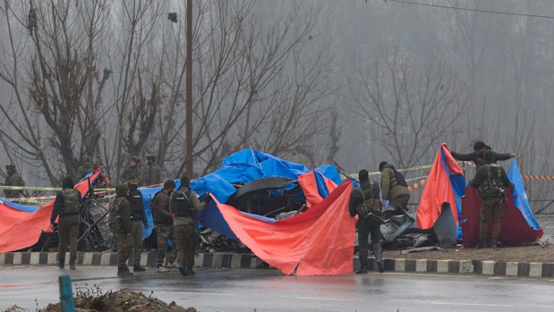 Indian policemen cover the wreckage of a bus with plastic sheets at the site of the explosion in Pampore, Indian-controlled Kashmir on February 15.