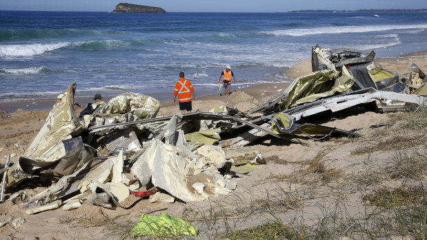 Workers inspect the remains of shipping containers washed up on Birdie Beach, NSW.