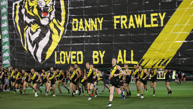 In memory: Richmond players run through the banner dedicated to AFL great Danny Frawley.