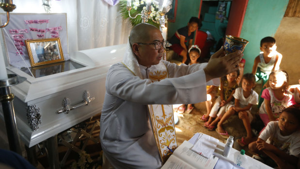 The mother of the slain girl Myka Ulpina sprinkles holy water at her coffin during a mass.