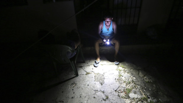 Steven Sands sits outside his home with a flashlight and his smartphone in the aftermath of Hurricane Maria.