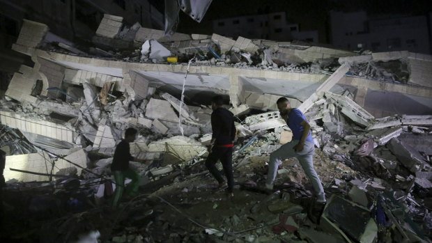 Owners of stores at the building inspect the damage of their destroyed multi-story building in Gaza City.