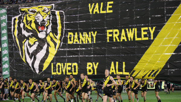 In memory: Richmond players run through the banner dedicated to AFL great Danny Frawley.