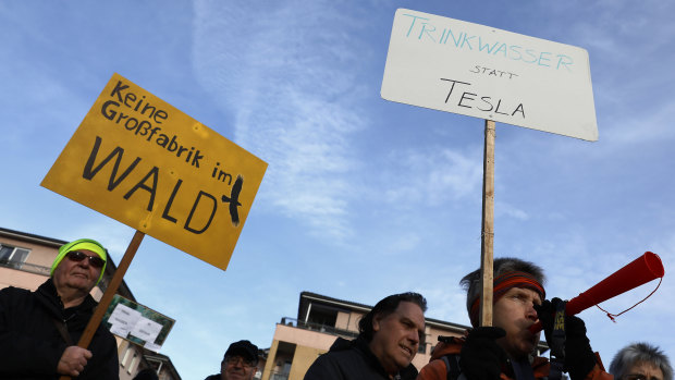 German protesters hold placards saying "No big factory in the forest" and "Drinking water instead of Tesla", as they demonstrate against the carmaker's planned factory last month.