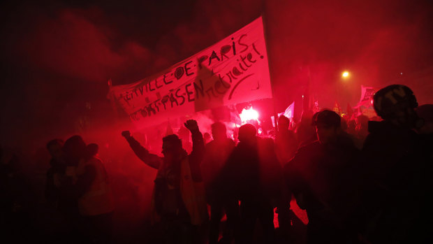 Flares illuminate the darkness at the end of a demonstration in Paris.