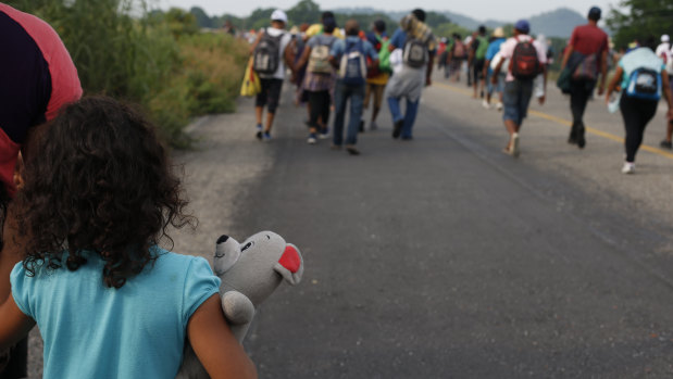 A girl carries a stuffed teddy bear as she walks with her mother with a migrant caravan near Arriaga, Chiapas state, Mexico, on  October 27.