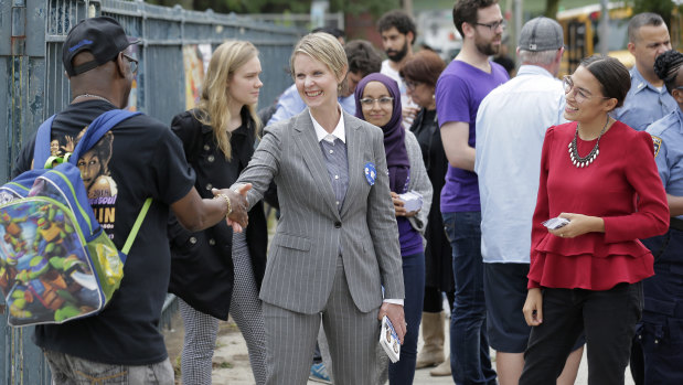Democratic gubernatorial candidate Cynthia Nixon, centre, and congressional candidate Alexandria Ocasio-Cortez, right, greet voters and children outside a school while campaigning in New York.