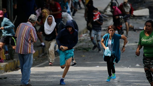 Anti-government protesters run during clashes with security forces as they show support for an apparent mutiny by a Venezuelan National Guard unit.