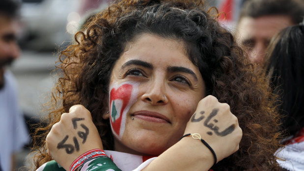 An anti-government protester displays the words "Revolution" left, and "Lebanon" right, in Arabic on her hands.