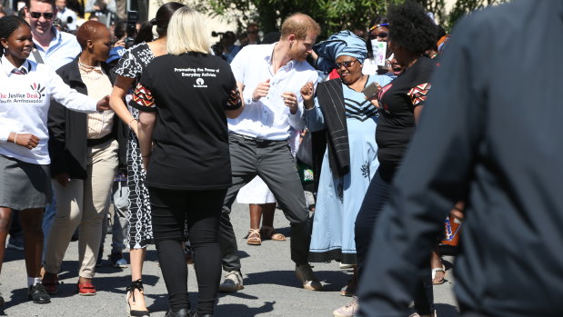 Prince Harry dances with well-wishers during a visit to The Justice Desk.
