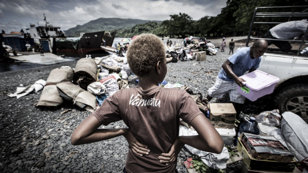 A young boy watches his family unload their possessions. 