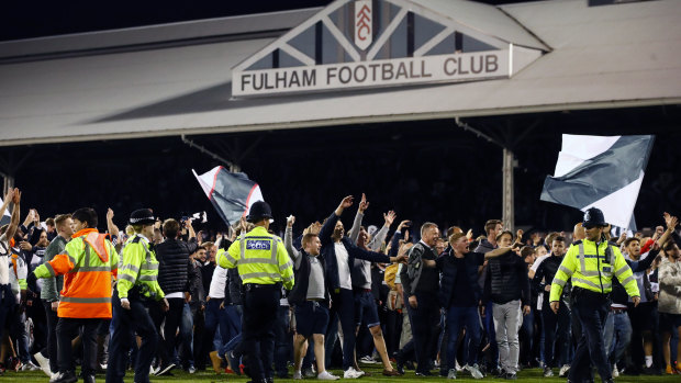 Fulham fans celebrate on the pitch.