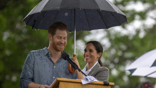 Dream team: Meghan shelters Prince Harry while he speaks at a community picnic.
