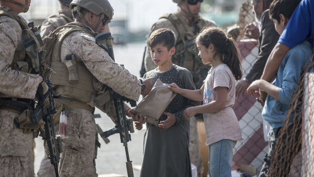 A US Marine opens a meal ready-to-eat package for children during an evacuation at Hamid Karzai International Airport in Kabul. 