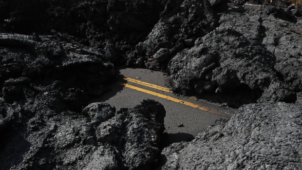 Centre lane lines are partially visible along the lava-covered road in the Leilani Estates subdivision near Pahoa.